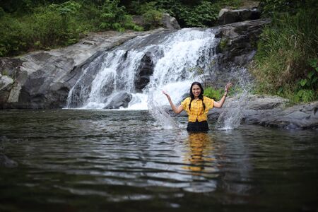 Women enjoying playing in the water at Khlong Nam Lai waterfall in Klong Lan national park, Kamphaeng Phet, Thailandの写真素材