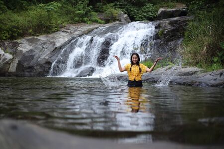 Women enjoying playing in the water at Khlong Nam Lai waterfall in Klong Lan national park, Kamphaeng Phet, Thailandの写真素材