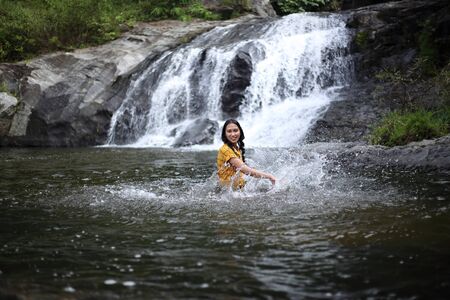 Women enjoying playing in the water at Khlong Nam Lai waterfall in Klong Lan national park, Kamphaeng Phet, Thailandの写真素材