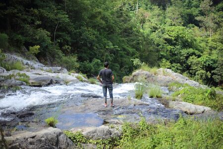 Man standing at Khlong Nam Lai waterfall in Klong Lan national park, Kamphaeng Phet, Thailandの写真素材