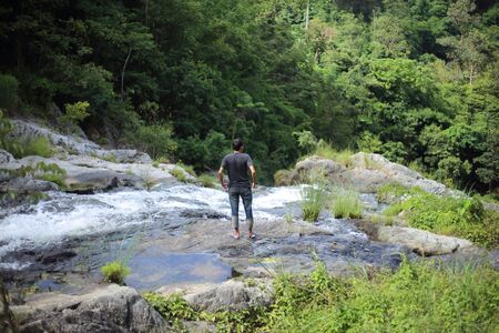 Man standing at Khlong Nam Lai waterfall in Klong Lan national park, Kamphaeng Phet, Thailandの写真素材