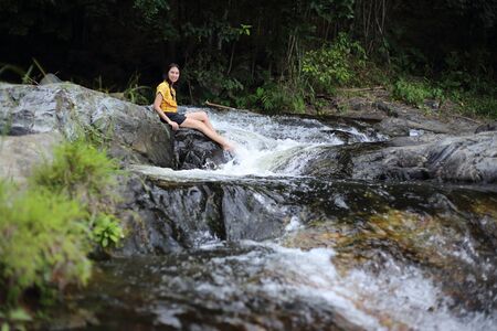 Woman sitting at Khlong Nam Lai waterfall in Klong Lan national park, Kamphaeng Phet, Thailandの写真素材
