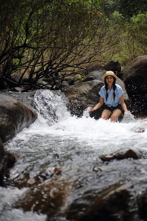 Woman sitting on a rock at Trok Nong Waterfall in Chanthaburi, Thailand
