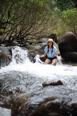 Woman sitting on a rock at Trok Nong Waterfall in Chanthaburi, Thailandの写真素材