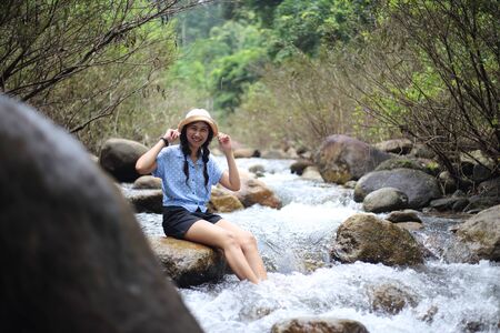 Woman sitting on a rock at Trok Nong Waterfall in Chanthaburi, Thailandの写真素材