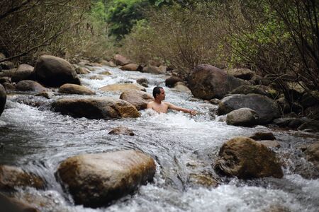A man is bathing in the Trok Nong waterfall in Chanthaburi, Thailand.の写真素材