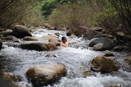 A man is bathing in the Trok Nong waterfall in Chanthaburi, Thailand.の写真素材