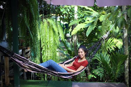 Woman sitting in garden with green plantsの写真素材