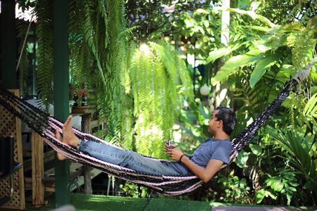 Man sitting in garden with green plantsの写真素材