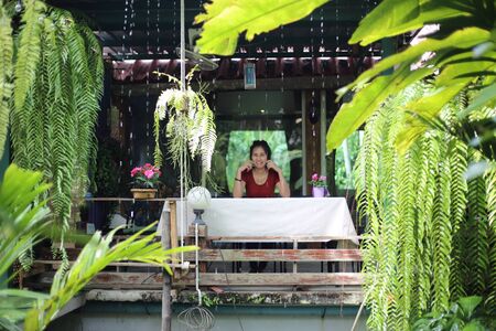 Woman sitting in garden with green plantsの写真素材