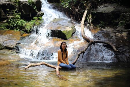 Woman sitting on a branch at Khao Chamao Waterfall, Thailandの写真素材