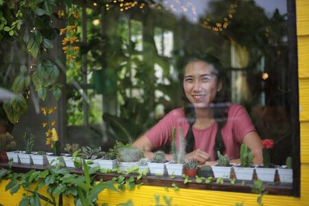Woman sitting and looking at the garden view through the glass roomの写真素材