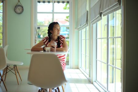 A woman sitting and drinking coffee in a cafeの写真素材