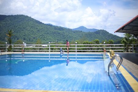 Woman standing at the pool area with mountain viewsの写真素材
