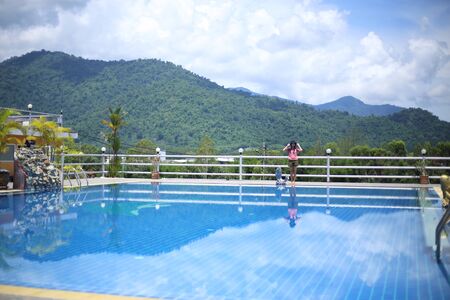 Woman standing at the pool area with mountain viewsの写真素材
