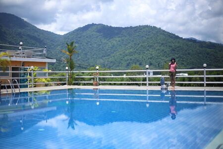 Woman standing at the pool area with mountain viewsの写真素材
