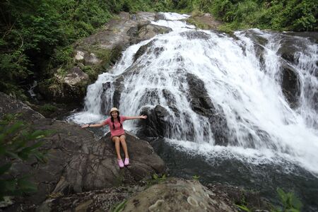 Woman sitting on the rocks at Khao Soi Dao waterfall in Chanthaburi, Thailandの写真素材
