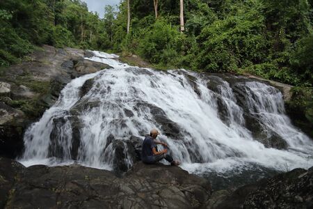Man sitting on the rocks at Khao Soi Dao waterfall in Chanthaburi, Thailandの写真素材