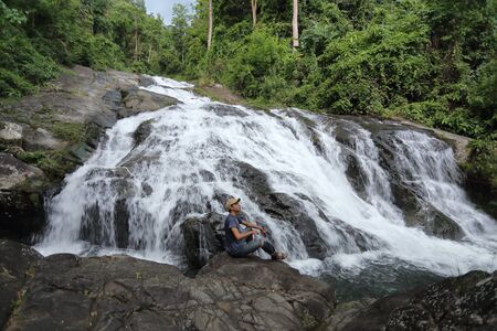 Man sitting on the rocks at Khao Soi Dao waterfall in Chanthaburi, Thailandの写真素材