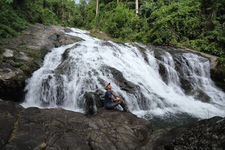Man sitting on the rocks at Khao Soi Dao waterfall in Chanthaburi, Thailandの写真素材