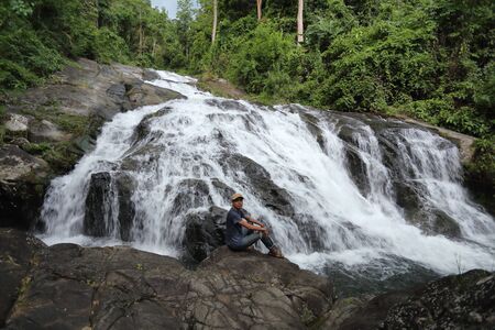 Man sitting on the rocks at Khao Soi Dao waterfall in Chanthaburi, Thailandの写真素材