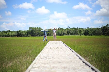 A woman standing on a wooden bridge in a rice fieldの写真素材