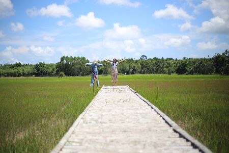 A woman standing on a wooden bridge in a rice fieldの写真素材