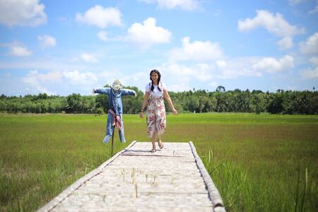 A woman standing on a wooden bridge in a rice fieldの写真素材