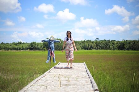 A woman standing on a wooden bridge in a rice fieldの写真素材