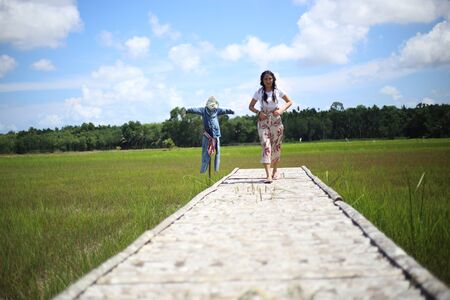 A woman standing on a wooden bridge in a rice fieldの写真素材