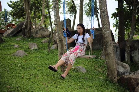 A woman sitting on a swing in the gardenの写真素材
