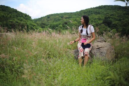 A woman sitting on a stone in a meadowの写真素材