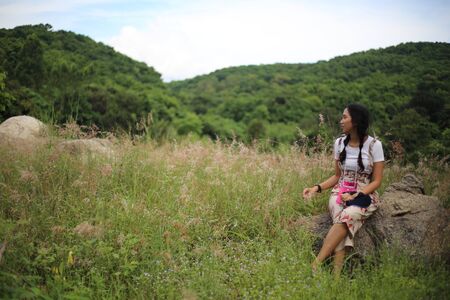A woman sitting on a stone in a meadowの写真素材