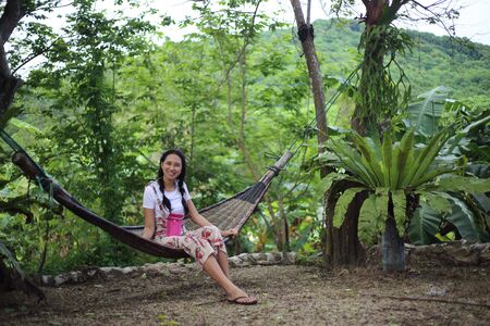 Woman sitting in a hammock in the gardenの写真素材
