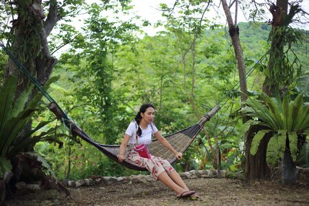 Woman sitting in a hammock in the gardenの写真素材
