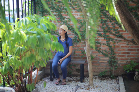 Portrait of Asian woman sitting on a bench in the garden.の写真素材