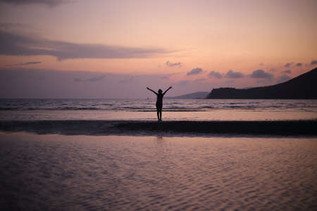 Silhouette of a person standing on the beach at sunset.の写真素材