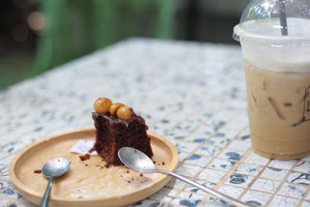 Chocolate cake with ice coffee on wooden plate in coffee shop.の写真素材