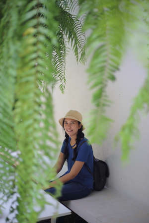 portrait of a beautiful asian woman wearing a hat and backpack sitting in a coffee shopの写真素材