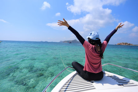 Young woman with arms outstretched sitting on a catamaran boatの写真素材