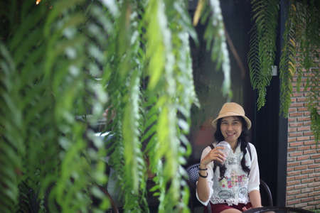 Portrait of asian woman wearing hat and drinking coffee in coffee shopの写真素材