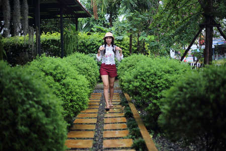 A young woman is walking on a wooden path in the garden.の写真素材