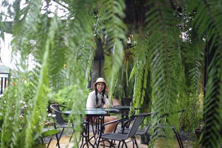 Portrait of a beautiful Asian woman sitting at a table in a garden.の写真素材