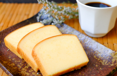 Homemade plain butter cake soft and moist. Slice of butter cake on plate and serve with black coffee on wood tableの写真素材