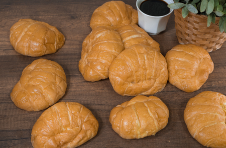 Freshly baked homemade croissants and black coffee on wooden cutting board, top viewの写真素材