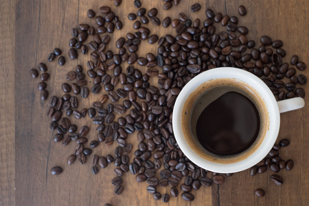 Coffee cup and coffee beans on wooden table backgroundの写真素材