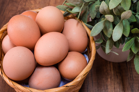 Fresh chicken eggs in basket on wooden table with space for textの写真素材