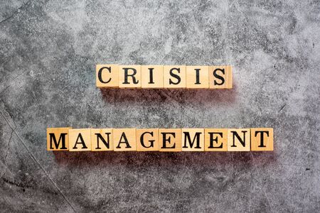 The letters on the wooden blocks that write the word crisis management on the black cement background.の写真素材