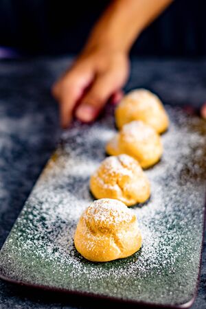 Eclair, choux filled vanilla custard cream and dusted with icing,  dessert on a plate with copy spaceの写真素材