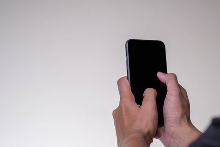 Close up Hand man holding smartphone with black screen isolated on yellow backgroundの写真素材